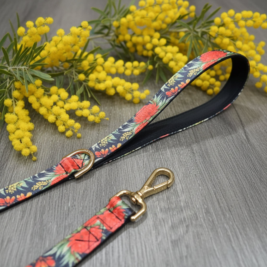 Floral patterned dog leash with brass clip on a wooden surface