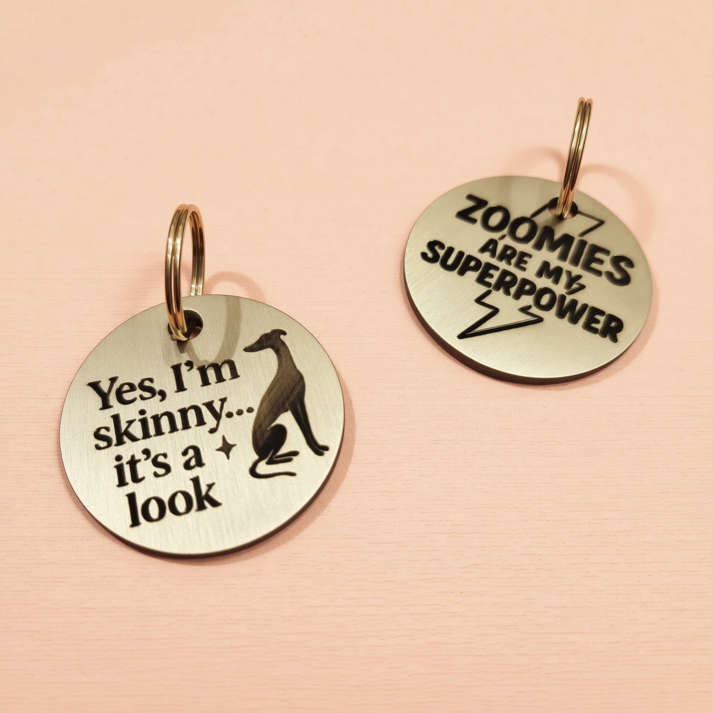 two round metal tags with humorous text and a silhouette of a dog.
