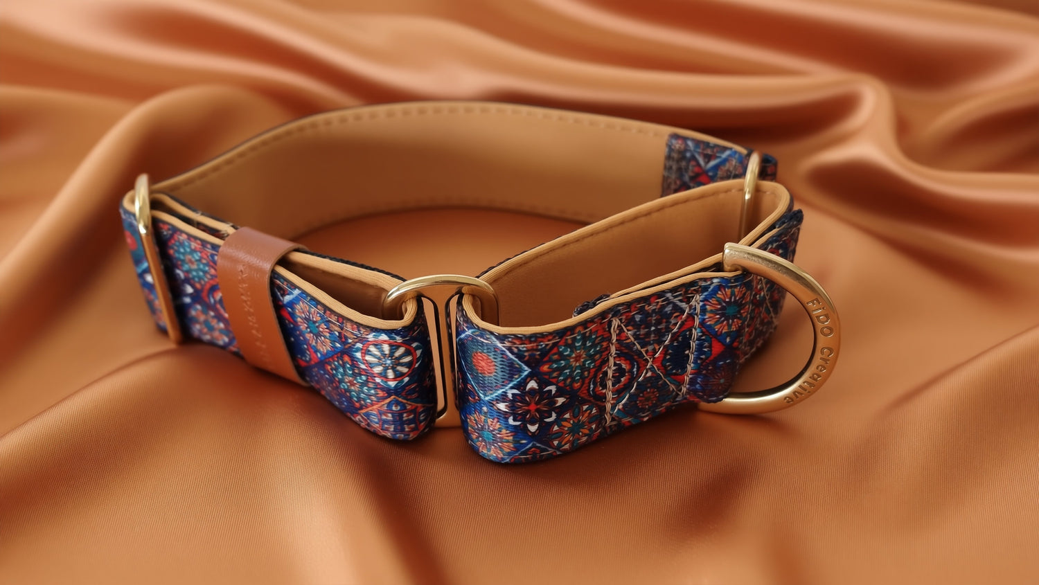 A colorful patterned dog collar with a gold-colored buckle and a gold-colored metal ring.
