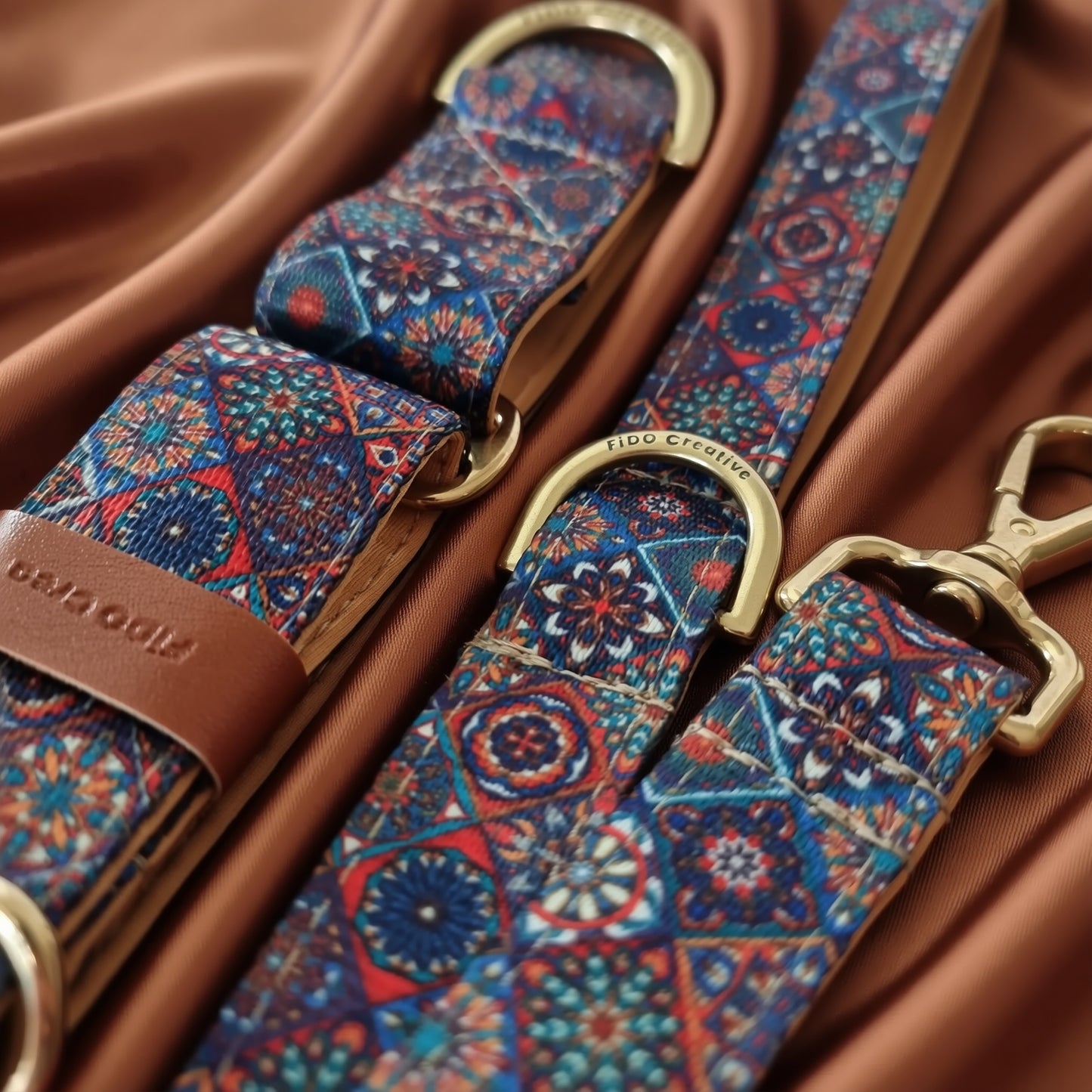 A close-up view of a colorful patterned dog collar and leash with a gold-colored metal buckle.