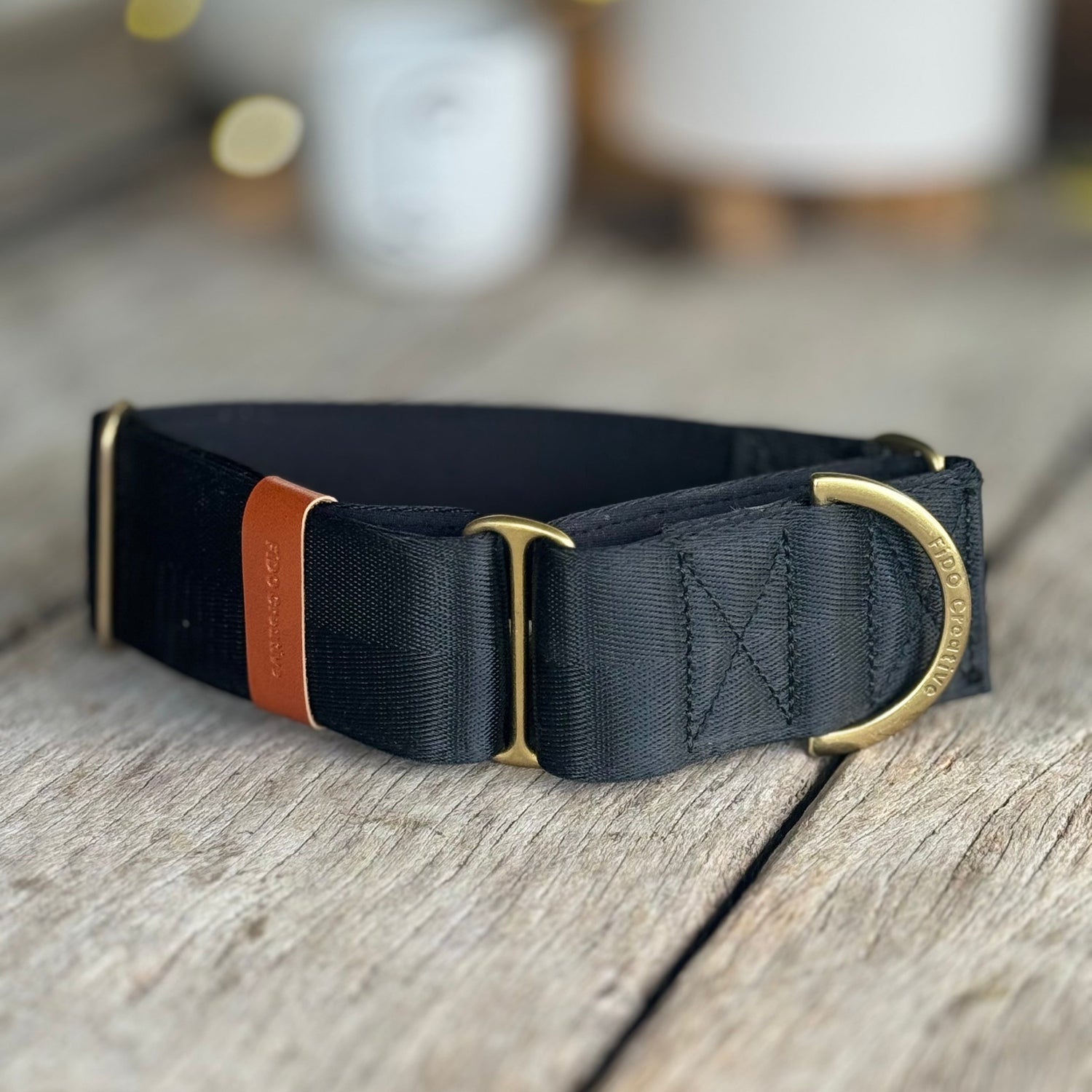 Black martingale dog collar with gold hardware on a wooden surface